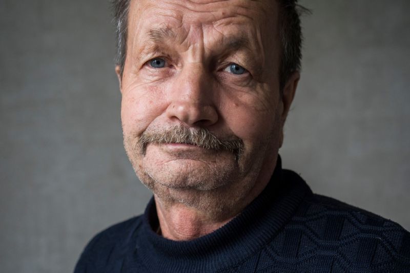 older man in a sweater with a straight face