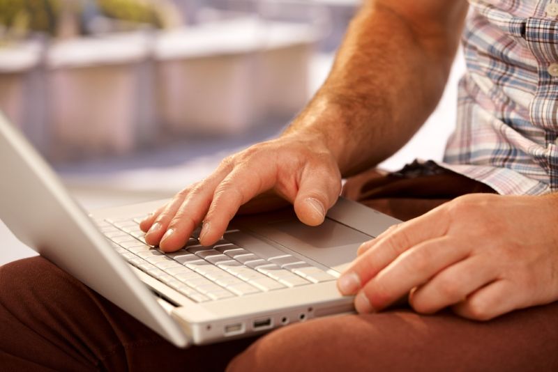 closeup of a man's hands typing on a laptop