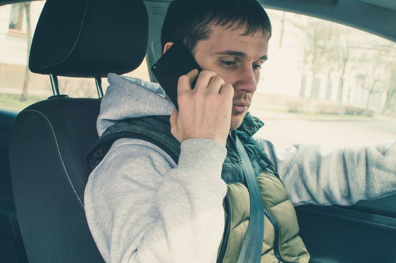 man making a phone call from the driver's seat of his car