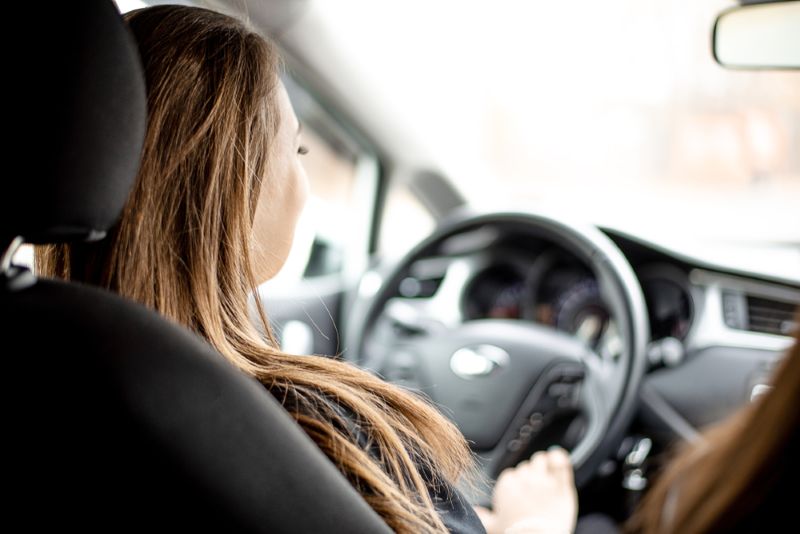View from behind of a woman driving a car during the day