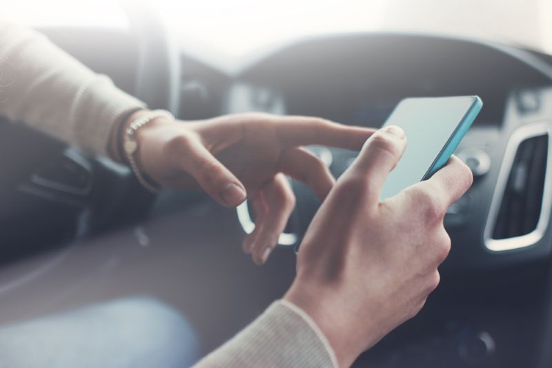 Closeup image of a person texting while driving